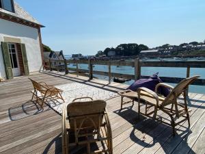 a group of chairs sitting on a deck next to the water at La maison du grand rocher in Ploubazlanec