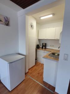 Una cocina con gabinetes blancos y un fregadero. en LA CASITA, en Düren - Eifel