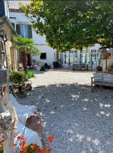 un parc avec des bancs, un arbre et un bâtiment dans l'établissement La maison du grand rocher, à Ploubazlanec