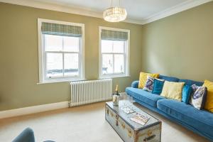 uma sala de estar com um sofá azul e duas janelas em Host & Stay - Henderson House em Whitby