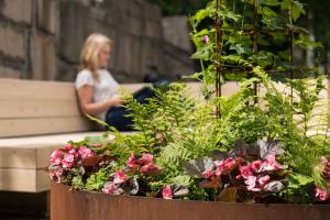 a woman sitting on a bench next to a pot of flowers at STF Hostel Stigbergsliden in Gothenburg