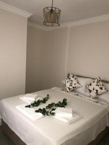ein Bett mit weißen Handtüchern und grünen Blättern darauf in der Unterkunft Apart TU Çeşme in Izmir