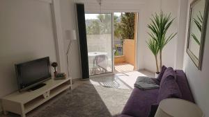 a living room with a purple couch and a tv at Sea view Apartment Peyia, Paphos in Paphos