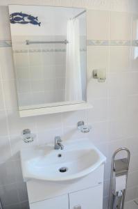 a white bathroom with a sink and a mirror at Kalokairi Cottage in Skopelos Town +40 photos