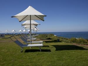 ターラントにあるIncanto delle Ninfeの浜辺の傘をさす一列のベンチ