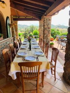 un lungo tavolo da pranzo su un patio con sedie di Hotel Janas a Tertenìa