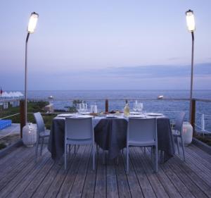 uma mesa de jantar e cadeiras num deque com o oceano em Incanto delle Ninfe em Taranto