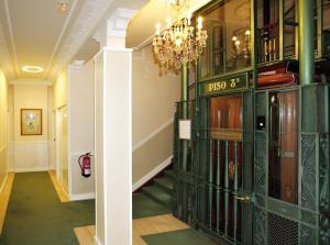 a hallway with green bookshelves and a chandelier at Hotel Niza in Donostia-San Sebastián