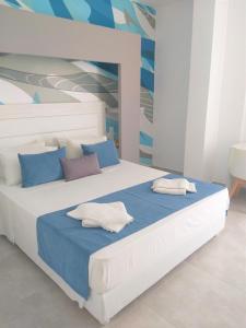 a bedroom with a bed with white and blue pillows at Sun Boutique Hotel (Adults Only) in Amoudara Herakliou
