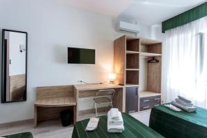 una stanza con due letti, una scrivania e una TV di Hotel Bellavista a Porto San Giorgio