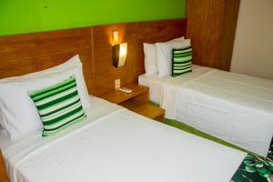 two beds in a hotel room with green walls at Quality Suites Natal in Natal