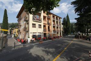 un bâtiment sur le côté d'une rue avec des tables et des chaises dans l'établissement Hotel Lido, à Torri del Benaco