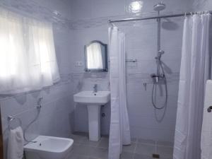 biała łazienka z umywalką i prysznicem w obiekcie Charlestina Beach Resort w mieście Ampeni