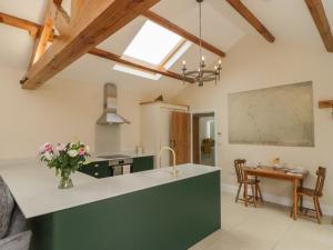 a kitchen with a green island and a table at Plough Cottage in Great Driffield