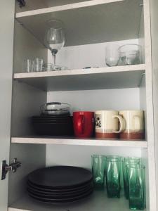 ein Regal mit Tellern und Gläsern und einem Weinglas in der Unterkunft Apartament 25 in Pisz