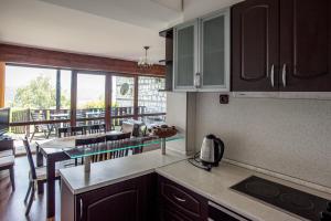 a kitchen with wooden cabinets and a balcony with a table at Вили Болярка in Kŭrdzhali