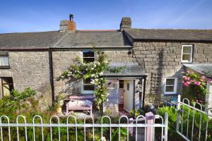 a stone house with a fence in front of it at Niver Dew Holiday Cottage in Lower Boscaswell