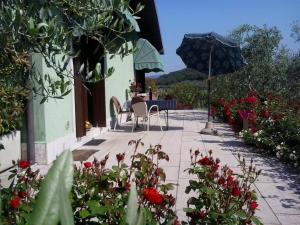 a patio with a table and an umbrella and flowers at Agriturismo la Casetta in Affi