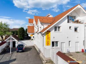 une maison blanche avec une voiture garée dans un parking dans l'établissement Pension Aquaris, à Sighişoara