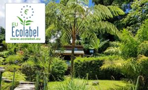 a sign in a garden with trees and plants at Les Bananes Vertes in Saint-Claude