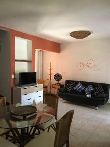 a living room with a black couch and a table at Cond Residencial Resort Pipa Chalés Triplex - Centro de Pipa in Pipa