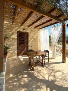 una mesa de madera en un patio bajo una pared de ladrillo en Le stanze di Ray, en Borgagne