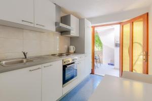uma cozinha com armários brancos e uma bancada em Eco-Apartments with nice garden em Baska Voda