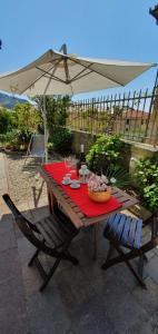 ein Holztisch mit Sonnenschirm und zwei Stühlen in der Unterkunft LE ORCHIDEE già Lancillotto in Levanto + 8 Fotos