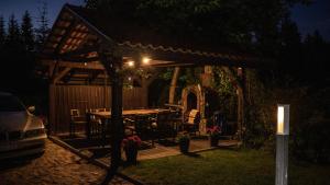 a pergola with a table and chairs in a yard at night at Pensjonat D&B in Gołdap