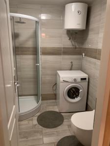 a bathroom with a shower and a washing machine at Apartman Annamaria in Cres
