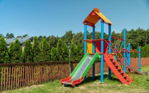 a playground with a slide in a yard at Dworek Bursztynowy in Karwia
