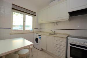 Una cocina blanca con fregadero y lavavajillas. en Casa Nau B, en Armação de Pêra