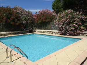 a swimming pool with pink flowers in a yard at Domaine du Petit Tournebelle in Gruissan