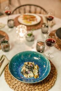 a blue plate of food on a table with wine glasses at Alacatı Port Ladera Hotel - Adult Only in Alaçatı