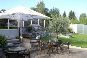 eine Terrasse mit Tischen, Stühlen und einem Sonnenschirm in der Unterkunft Haus Schieferstein in Dahlem