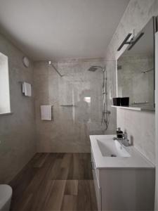 a white bathroom with a sink and a shower at Yellow Dreamhouse in Postojna