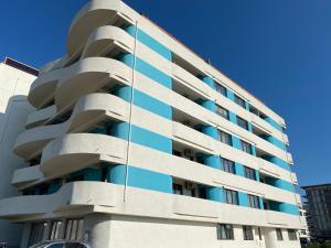 un grand bâtiment blanc avec des fenêtres bleues dans l'établissement MMA Sunset Vibes Mamaia Nord, à Mamaia Nord – Năvodari