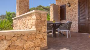 a patio with a table and chairs and a stone wall at Residence Il Corallo - Guitgia in Lampedusa