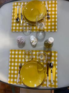 une table avec plaques jaunes et argenterie sur une table dans l'établissement A casa di Eugenio, à Carini