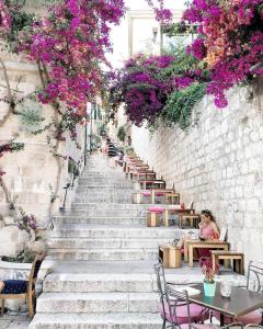 una escalera con mesas, sillas y flores púrpuras en Apartments Luči en Hvar