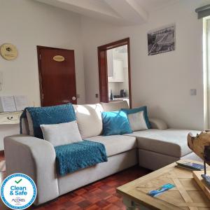 uma sala de estar com um sofá branco e almofadas azuis em Margarida House - Stone Apartment na Ribeira Grande