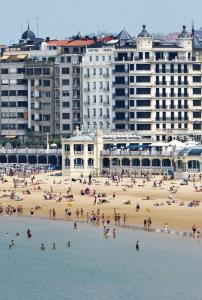 a group of people on a beach with buildings at Hotel Niza in Donostia-San Sebastián