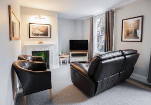 a living room with a leather couch and a television at The Green Leaf Apartment in Bath