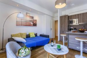 a living room with a blue couch and a kitchen at MY CASA - MEYERBEER in Nice