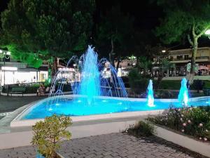 a fountain with blue water in a park at night at Mariza Apartments -studios in Hanioti