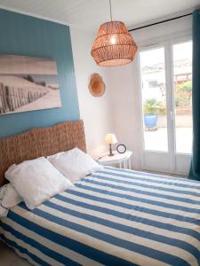 a bedroom with a blue and white striped bed and a window at Les portes du soleil in Les Sables-d'Olonne