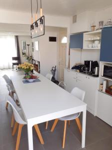 uma mesa de jantar branca e cadeiras numa cozinha em Les portes du soleil em Les Sables-dʼOlonne