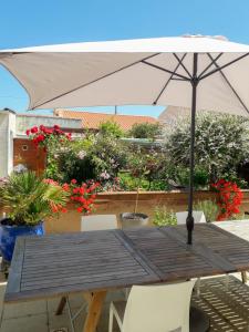 una mesa de madera con sombrilla y algunas plantas en Les portes du soleil en Les Sables-dʼOlonne