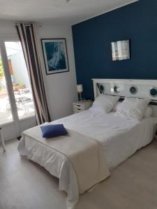 um quarto com uma grande cama branca e uma parede azul em Les portes du soleil em Les Sables-dʼOlonne