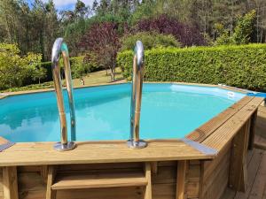 una piscina con 2 barras de metal junto a una terraza de madera en casa Francelos, en Rois